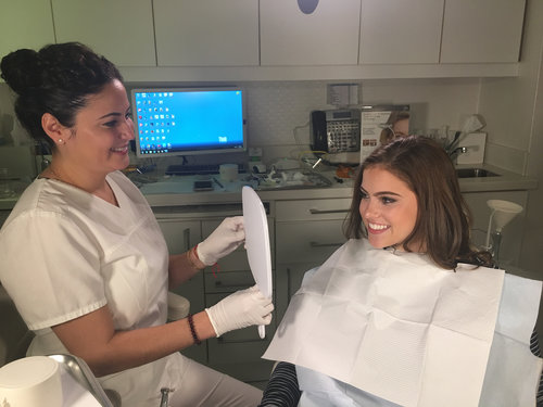 Young female patient admiring her new smile with female dentist