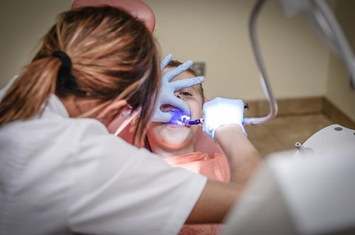 Female dentist treating young girl patient